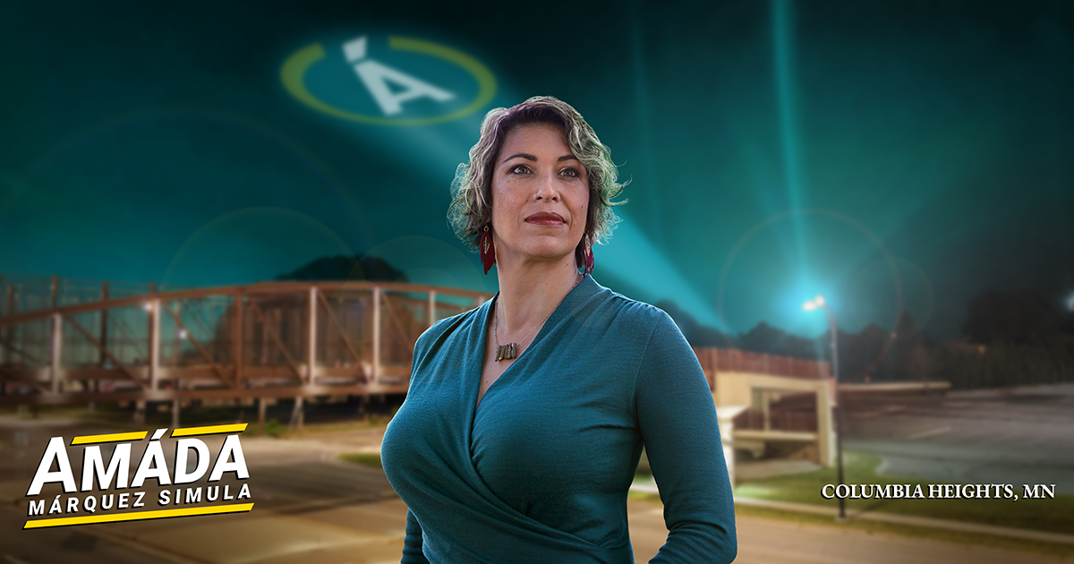 Like a hero, Amáda Márquez Simula looks over the city near the Central Avenue footbridge. A searchlight featuring her circular Á insignia illuminates the night sky.