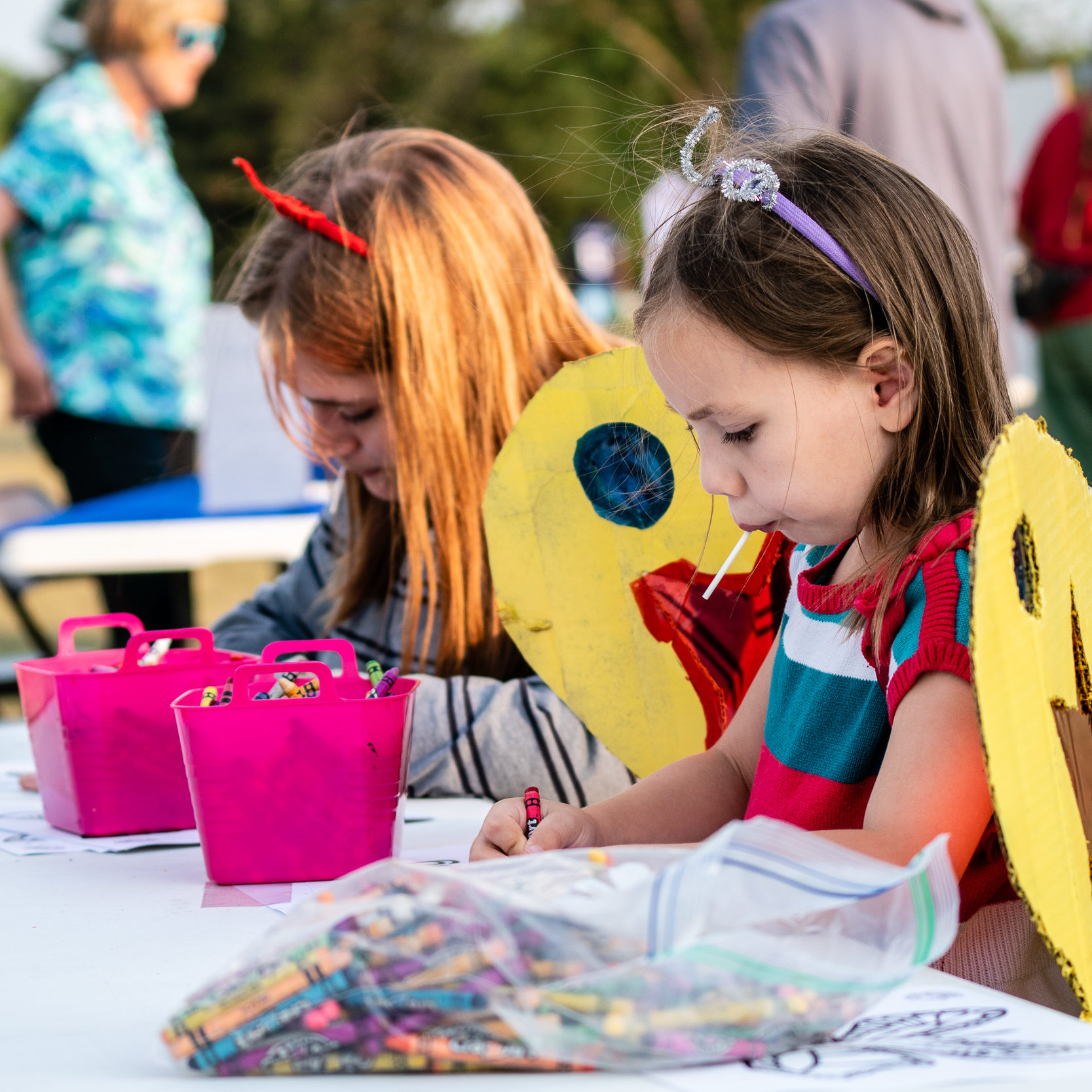 Kids dressed in butterfly wings do a coloring activity at the Columbia Heights Monarch Festival.