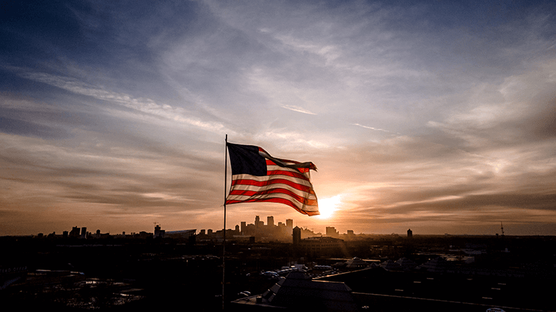 An American flag flies over the Minneapolis skyline at sunset