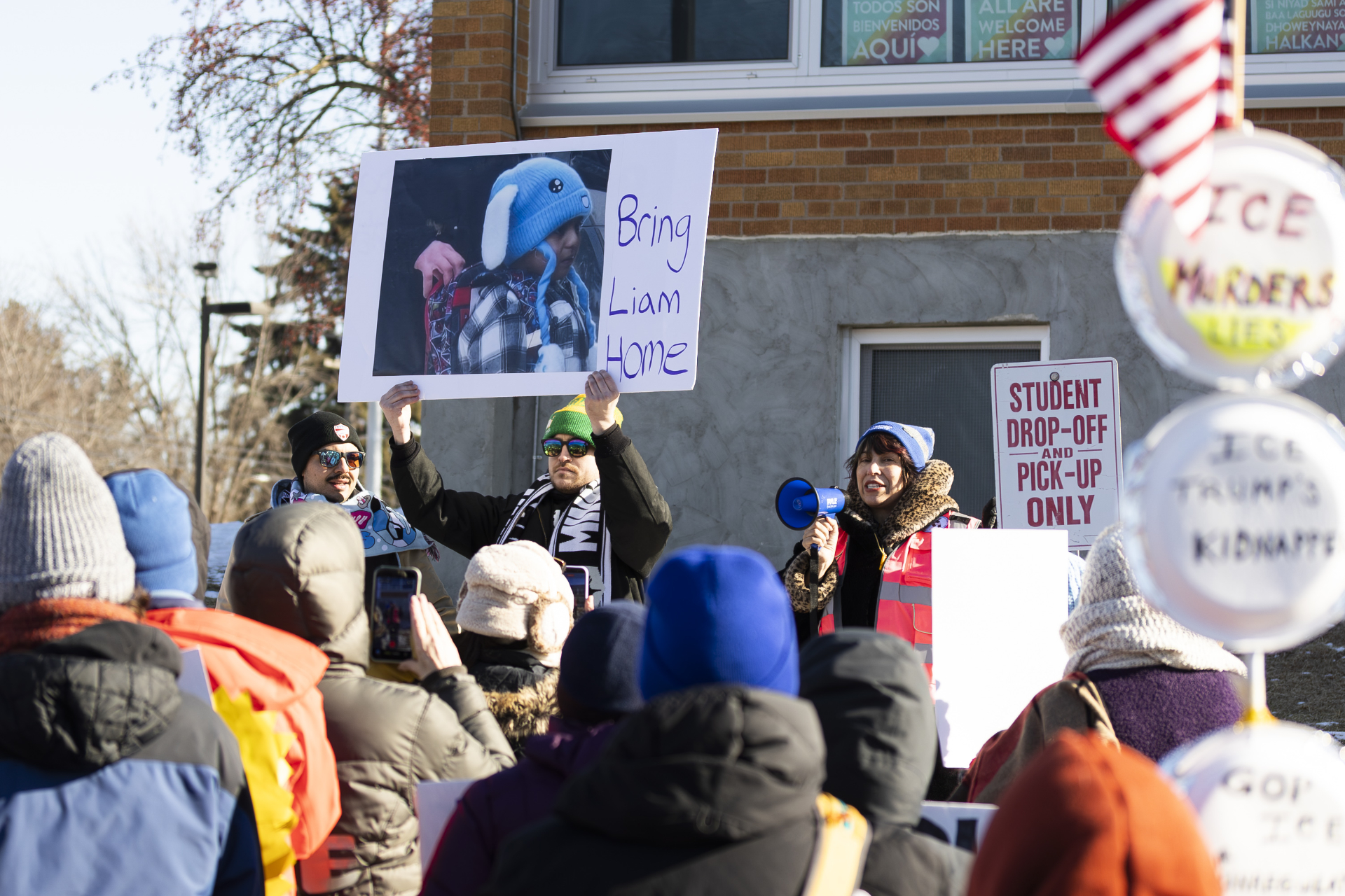 Amáda Márquez Simula rallies protestors against ICE at Valley View Elementary School in Columbia Heights, MN. A sign reads 'Bring Liam Home' with an iconic photo of a 5 year old child wearing a blue bunny hat being abducted by agents.